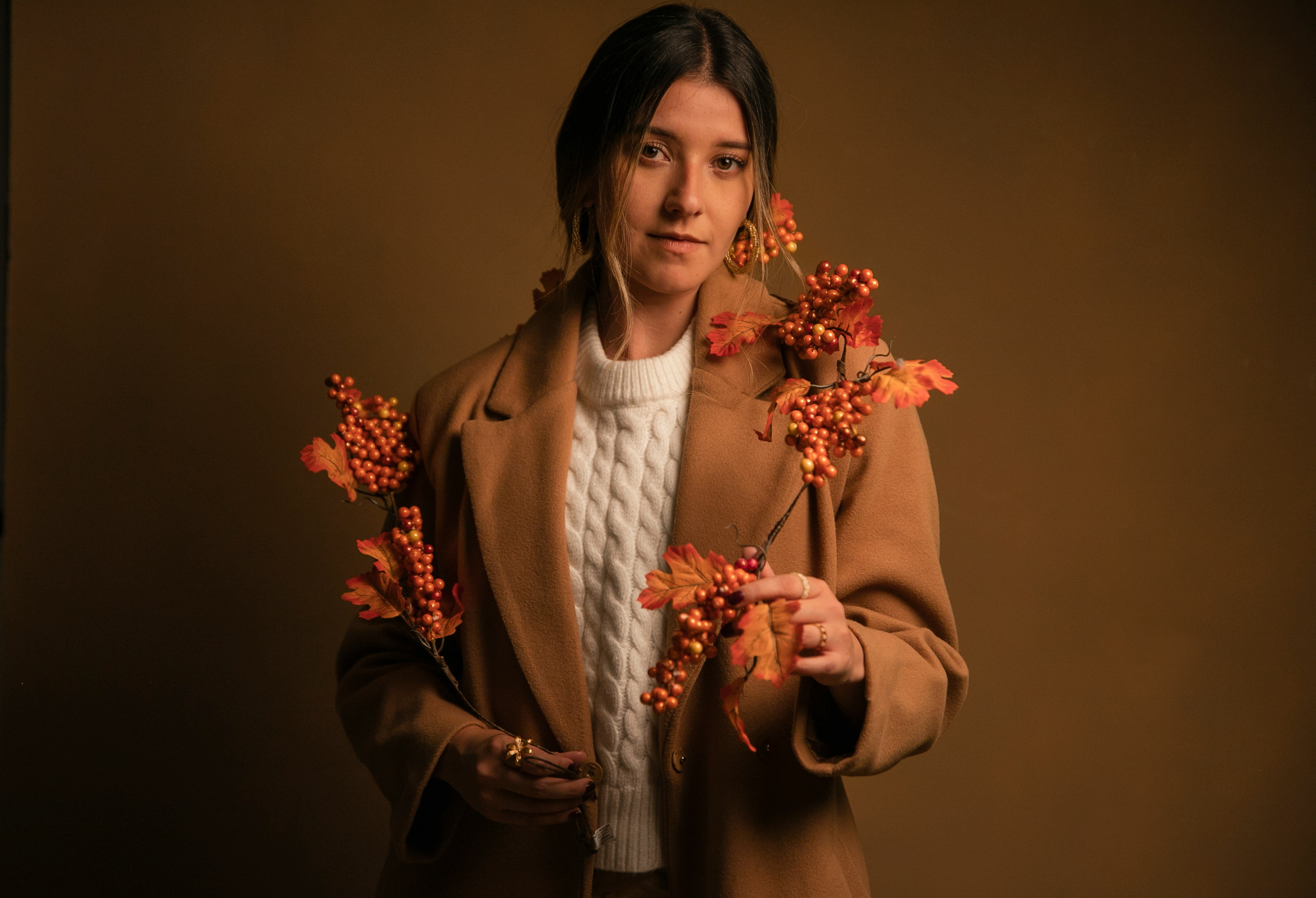 Woman holding autumn leaves against a brown background